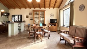 A spacious living area with a wooden ceiling, a dining table with chairs, a sofa, a television, and a kitchen area with a microwave and cabinets. - Detached house: relaxation.  CIR 19087053C261141 CIN IT087053C2WIFBFSGJ (Sicilia)