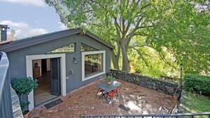 A patio with a table and chairs, a stone wall, and a large tree. - Detached house: relaxation.  CIR 19087053C261141 CIN IT087053C2WIFBFSGJ (Sicilia)