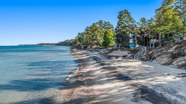 A beach with clear water, a sandy shore, and trees along the edge.