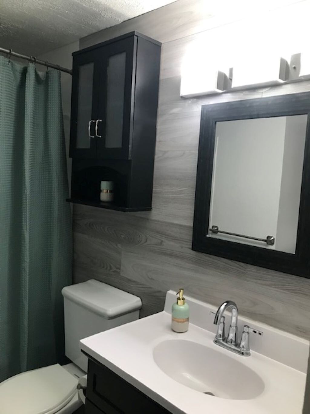 A bathroom with a white sink, a mirror, a cabinet, and a toilet.