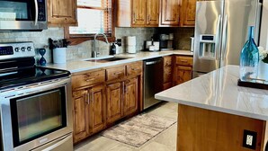 Una cocina moderna con armarios de madera, electrodomésticos de acero inoxidable y encimera de mármol.