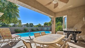 Um pátio externo com piscina, churrasqueira e mesa com cadeiras.