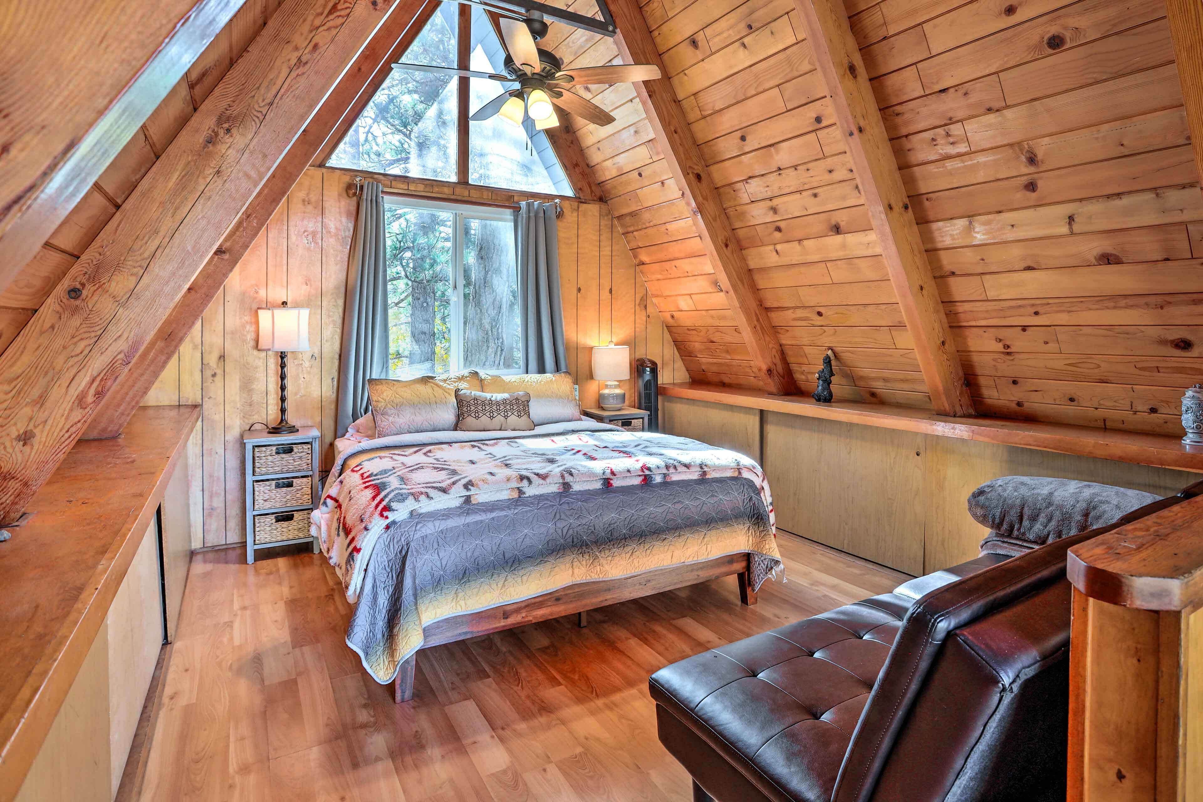 Un dormitorio acogedor con paneles de madera, una cama grande, un banco y una ventana.