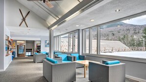 A spacious indoor area with wicker furniture, large windows, and a view of a mountainous landscape. - Lincoln Escape w/ Deck: 1 Mi to Loon Mountain! (Lincoln)