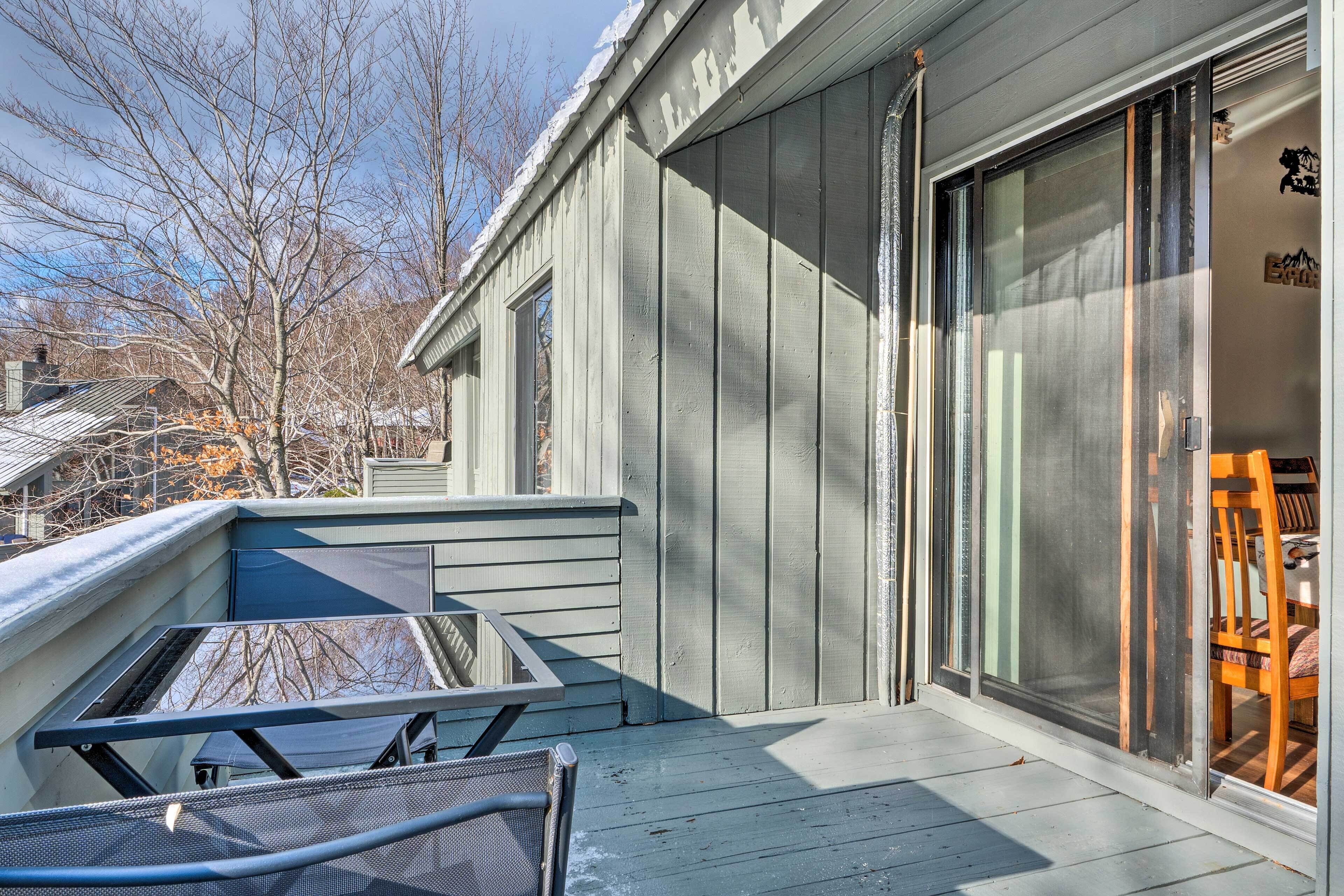 A covered outdoor area with a metal table and chairs, a sliding glass door, and a view of a house with a garage.