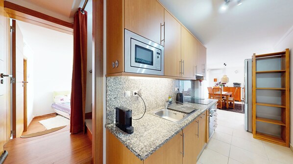 Een moderne keuken met granieten aanrechtbladen, roestvrijstalen apparatuur en houten keukenkastjes.