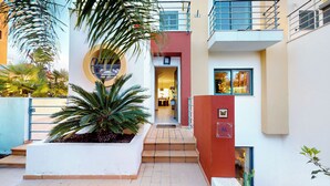 A modern building with a central courtyard, a staircase leading to an upper level, and a door with a butterfly decoration. - Vila Vida (8) | Private Heated Pool | Sea & Beach | Roof Terrace | Restaurants (Ferragudo)