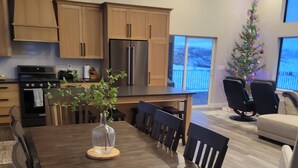 Una cocina moderna con armarios de madera, un refrigerador de acero inoxidable y un comedor con mesa y sillas de madera.