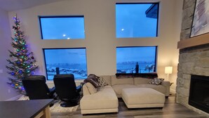 Una sala moderna con chimenea, ventanas amplias, un árbol de Navidad y un comedor.