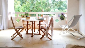 A balcony with a table and chairs, a hanging plant, and a folding chair. - Charming duplex apartment "Les pieds dans l'eau" N°7, 70 m from the beach. (Lecci)