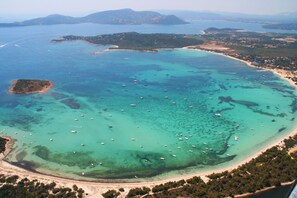 An aerial view of a coastal area with clear turquoise waters, numerous boats, and a sandy beach. - Charming duplex apartment "Les pieds dans l'eau" No. 7, 70 m from the beach (Lecci)