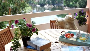 A wooden table with a tray of fruits, a book, and a magazine. A wicker chair and a potted plant with purple flowers are also visible. - Charming duplex apartment "Les pieds dans l'eau" N°7, 70 m from the beach. (Lecci)