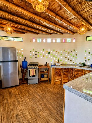A kitchen with a wooden ceiling, a stainless steel refrigerator, a gas stove, and a wooden cabinet. - Breathtaking Sea View Apartment Casa Xochi  (San Agustinillo)