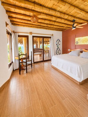 A room with a bed, a chair, a table, and a view through a glass door. - Breathtaking Sea View Apartment Casa Xochi  (San Agustinillo)