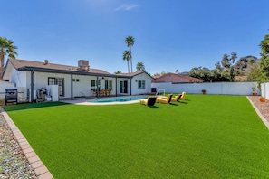 A backyard with a swimming pool, artificial grass, and outdoor furniture. - Scottsdale/Phoenix Home with Heated Pool (Phoenix)