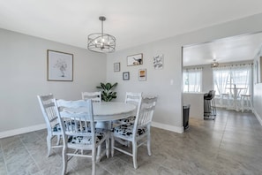 A dining area with a round table, white chairs, and a central plant. There are framed pictures on the walls and a chandelier above the table. - Scottsdale/Phoenix Home with Heated Pool (Phoenix)