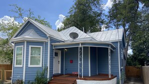 Ein blaues Haus mit Veranda und Eingangstür.