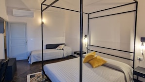 Une chambre avec un lit à baldaquin, un deuxième lit, un bureau et une chaise.