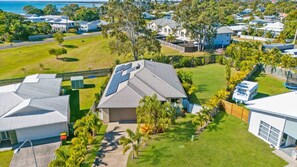 A residential area with houses, solar panels, and a view of the sea.