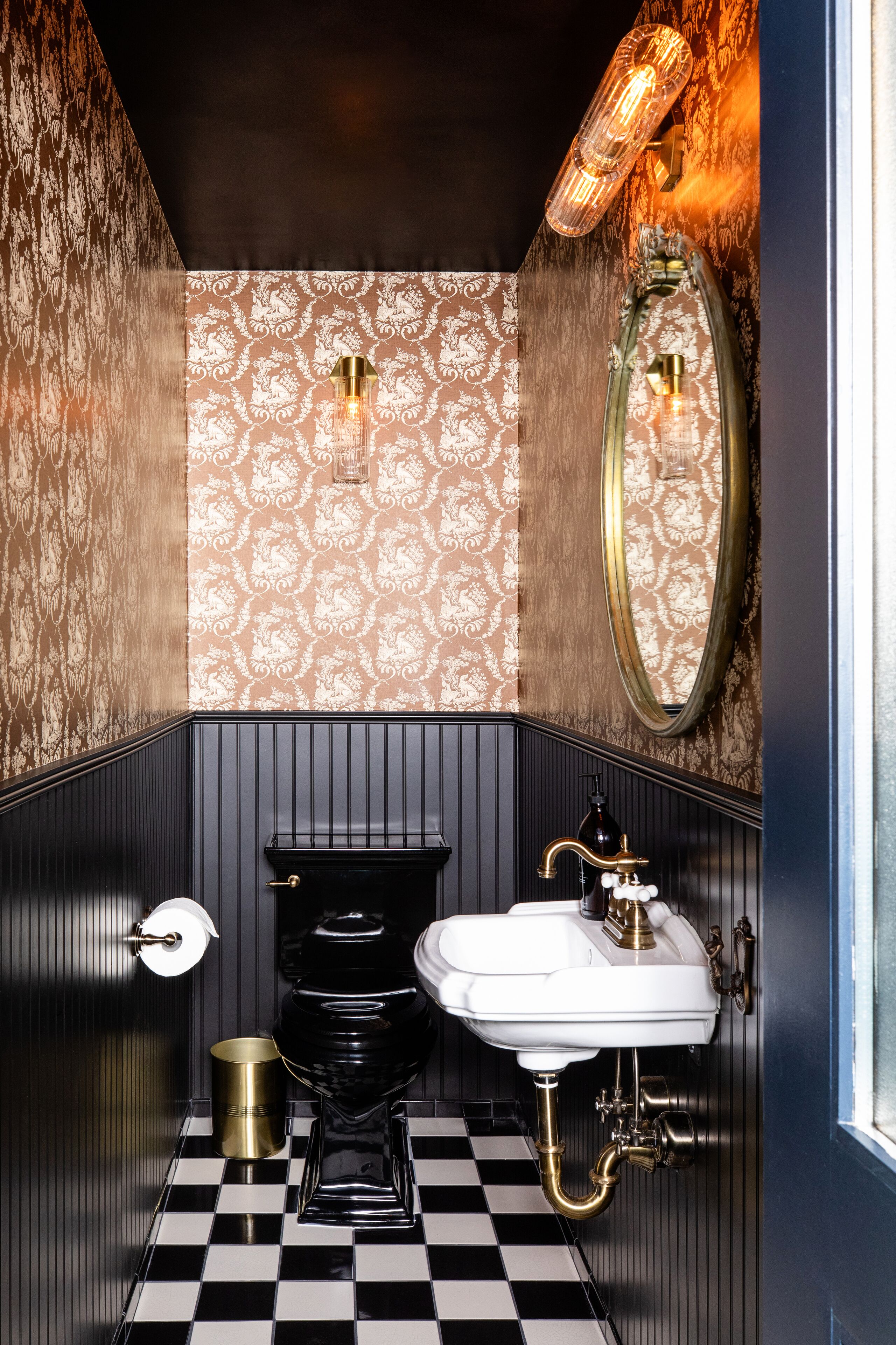 Ein Badezimmer mit Schachbrettboden, Toilette, Waschbecken und Spiegel.