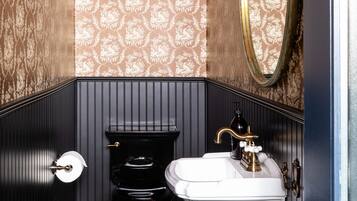 Ein Badezimmer mit Schachbrettboden, Toilette, Waschbecken und Spiegel.