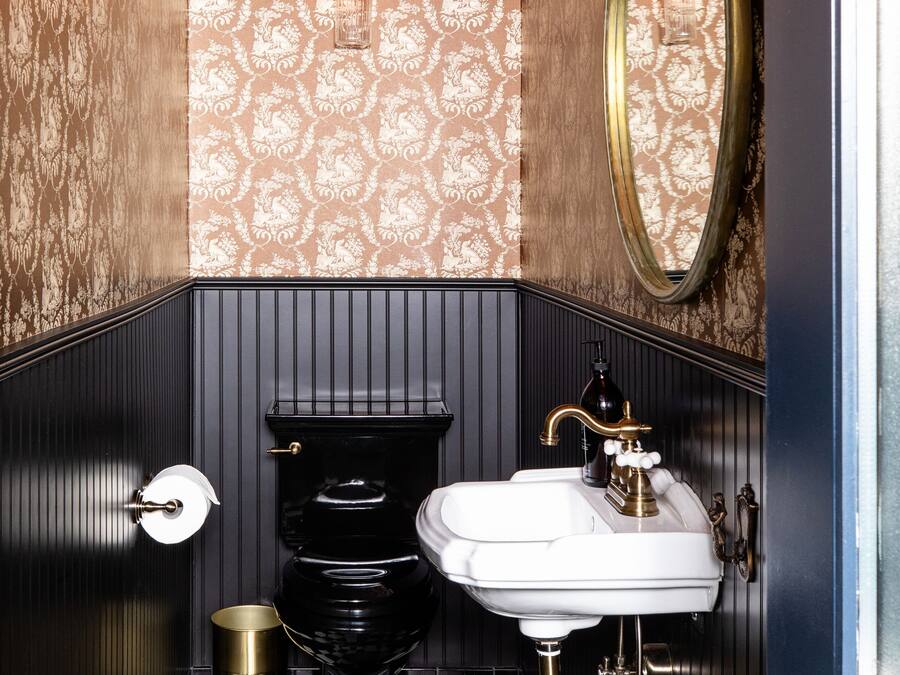 Ein Badezimmer mit Schachbrettboden, Toilette, Waschbecken und Spiegel.