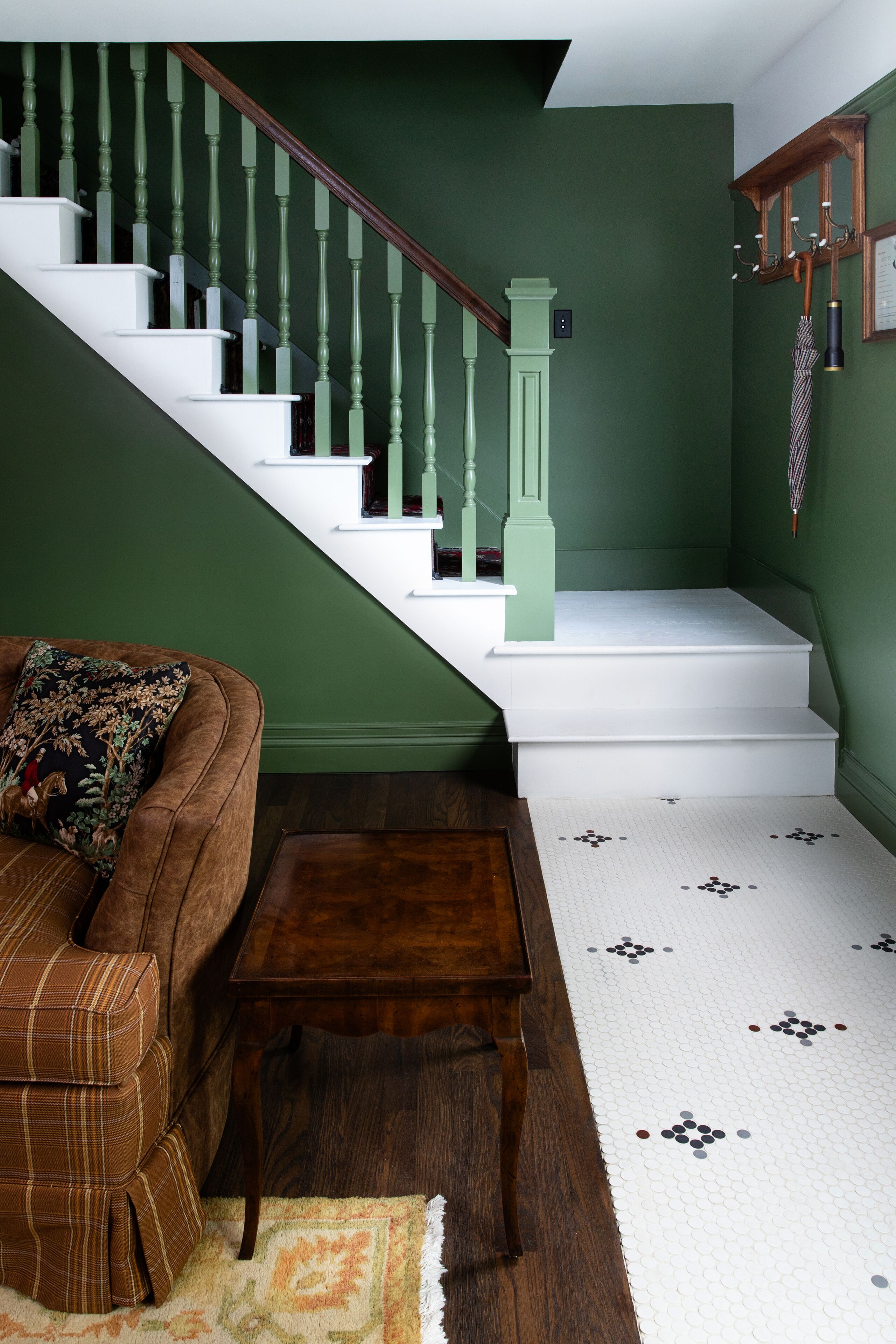 A staircase with green walls and white steps, a brown leather sofa, and a wooden coffee table.