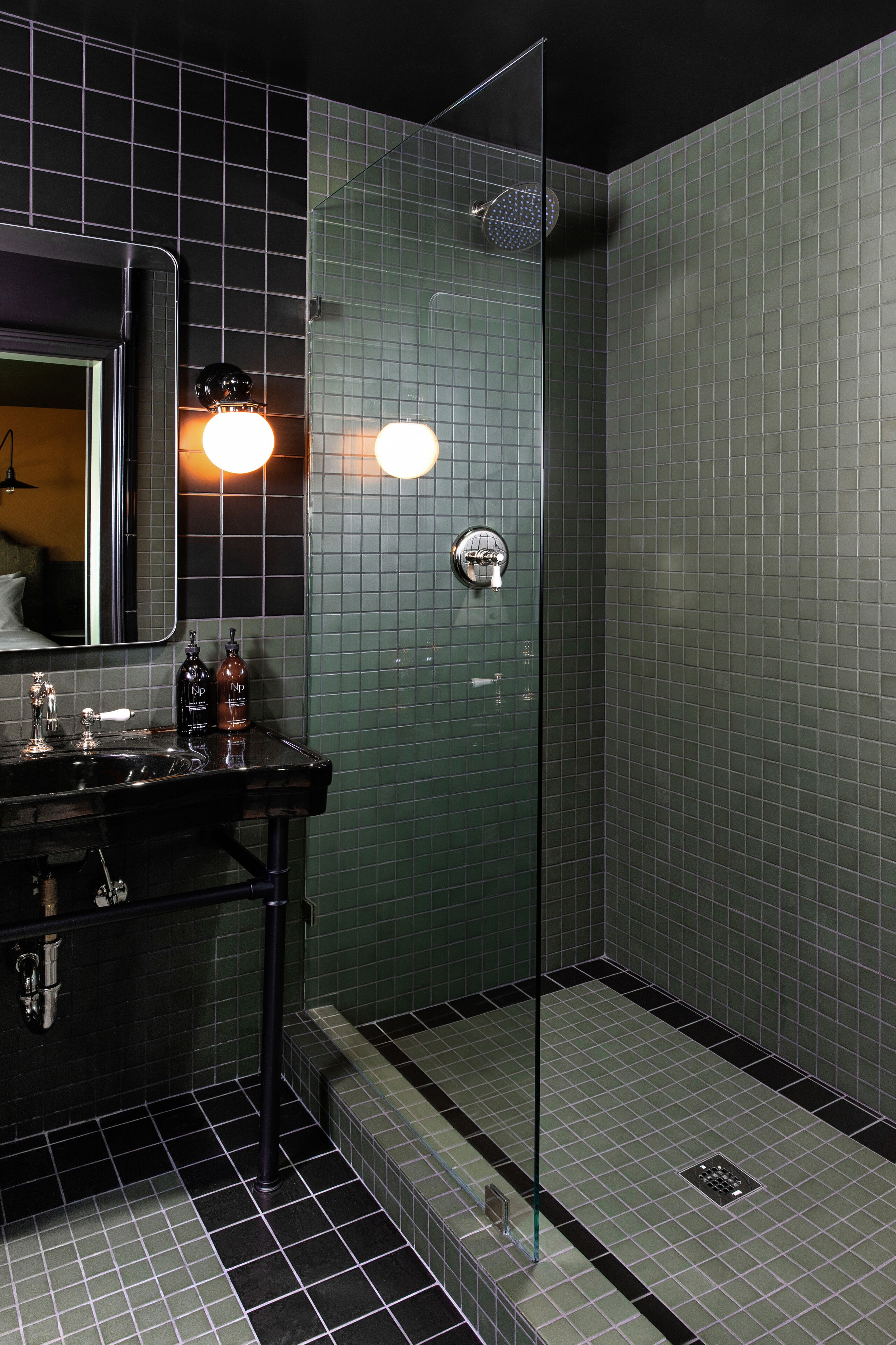 Une salle de bain moderne avec une douche à parois de verre, un lavabo avec un miroir et des murs carrelés.