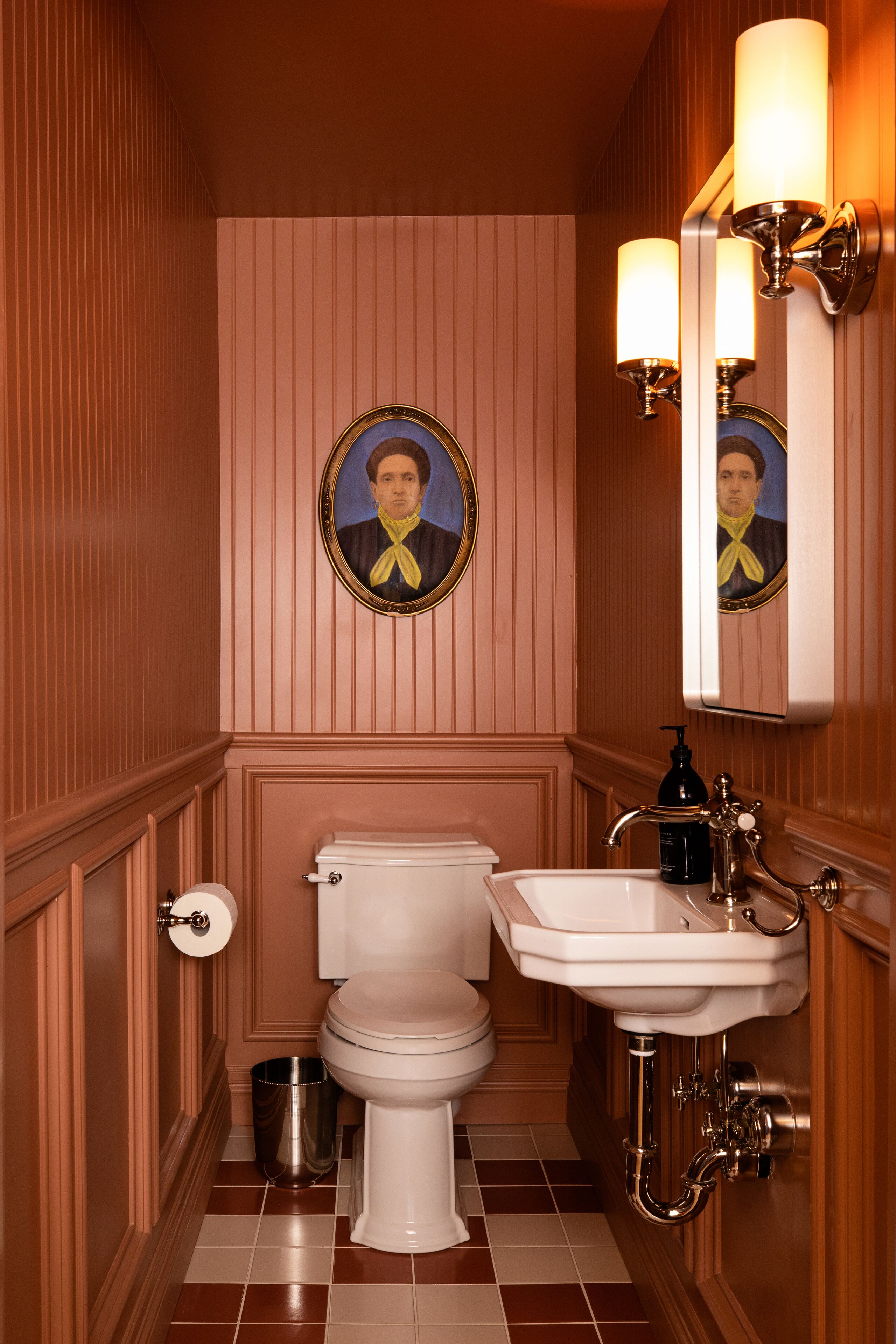 A bathroom with a toilet, sink, and mirror.