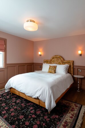A neatly made bed with white linens, a floral headboard, and a round bedside table. - N+P Boutique Lodge (Big Bear Lake)