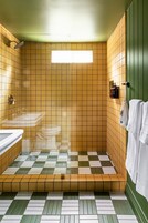 Um banheiro com piso quadriculado, parede verde e uma janela.