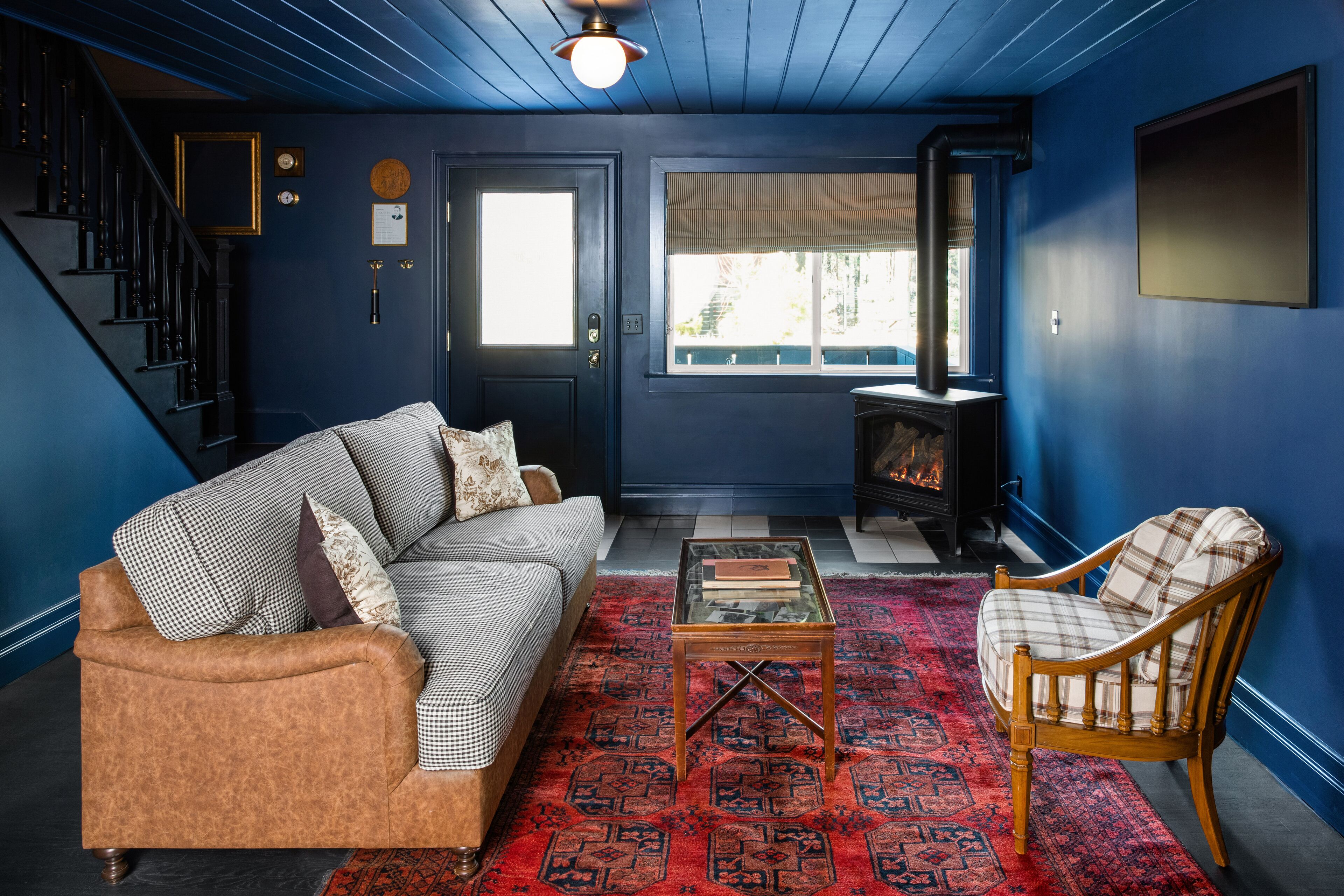 Een woonkamer met een blauwe wand, een bank, een fauteuil, een salontafel en een open haard.