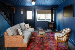 A living room with a blue wall, a sofa, a chair, a coffee table, and a fireplace. - N+P Boutique Lodge (Big Bear Lake)