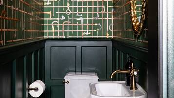 A bathroom with a checkered floor, a toilet, a sink, and a wall with a green grid pattern.