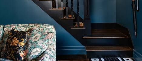 A staircase with dark wooden steps and balusters, a floral-patterned sofa, a small wooden table, and a patterned rug.