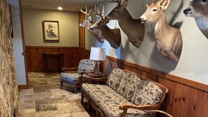 A room with a stone wall, a wooden bench, a patterned sofa, and a wall-mounted deer head. - Cozy house nestled in the country (Linn)