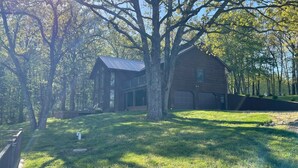 A wooden house with a garage, surrounded by trees and a grassy yard. - Cozy house nestled in the country (Linn)
