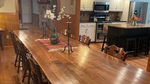 A spacious dining area with a long wooden table, surrounded by chairs, and a chandelier. - Cozy house nestled in the country (Linn)