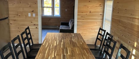 A wooden-paneled room with a large dining table and chairs, a window, and a built-in bench.