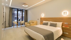 Ett modernt hotellrum med en stor säng, en soffa, ett matbord och utsikt över stadsbilden genom fönstret.