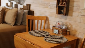 A wooden dining table with two chairs, a woven placemat, and a small wooden cabinet with decorative items. - Fish Cabin at Mountain View Retreat (Talihina)