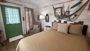 A room with a bed, a chair, a green door, and a hammock. - Fish Cabin at Mountain View Retreat (Talihina)