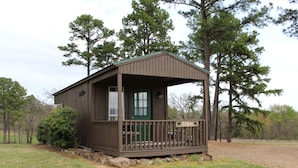 A small wooden cabin with a porch, surrounded by trees. - Fish Cabin at Mountain View Retreat (Talihina)