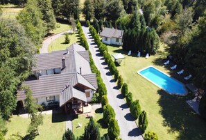 A residential property with a swimming pool, multiple houses, and a well-maintained lawn. - Cabin #3 (Araucanía)