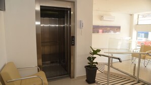 An elevator in a hotel lobby with a potted plant and a chair. - Boa Esperança Apart Hotel (Boa Esperanca)
