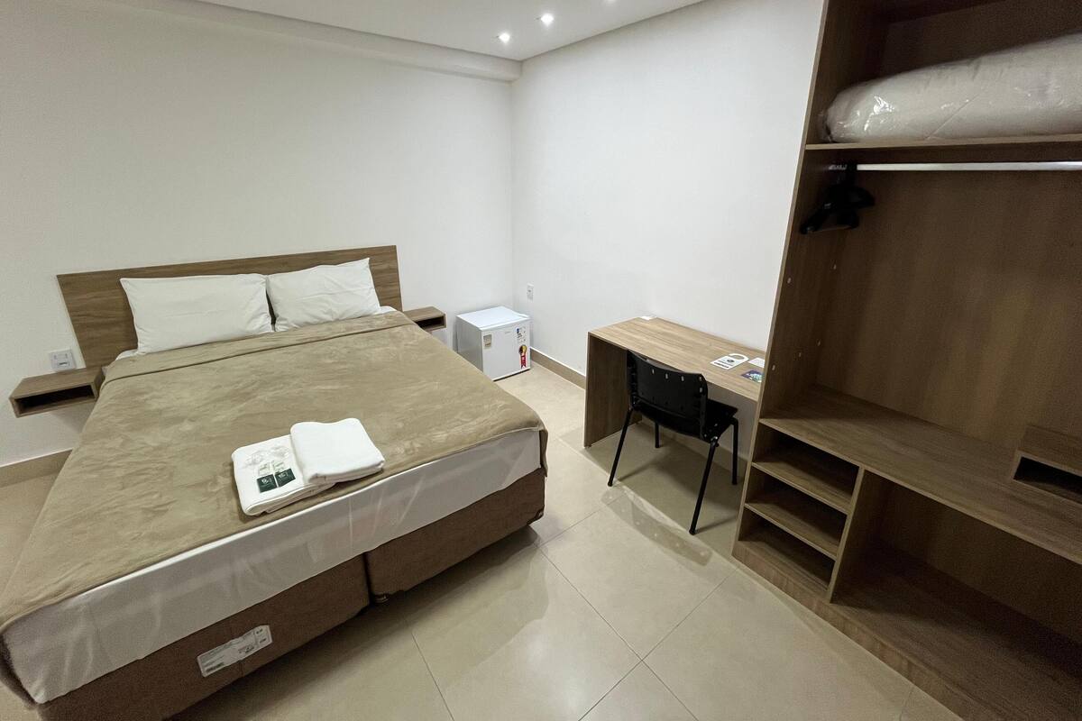 Una habitación de hotel moderna con una cama grande, un escritorio y un armario.
