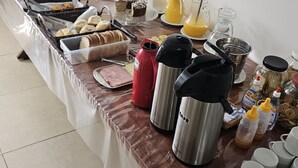 A buffet table with various food items, beverages, and containers. - Boa Esperança Apart Hotel (Boa Esperanca)