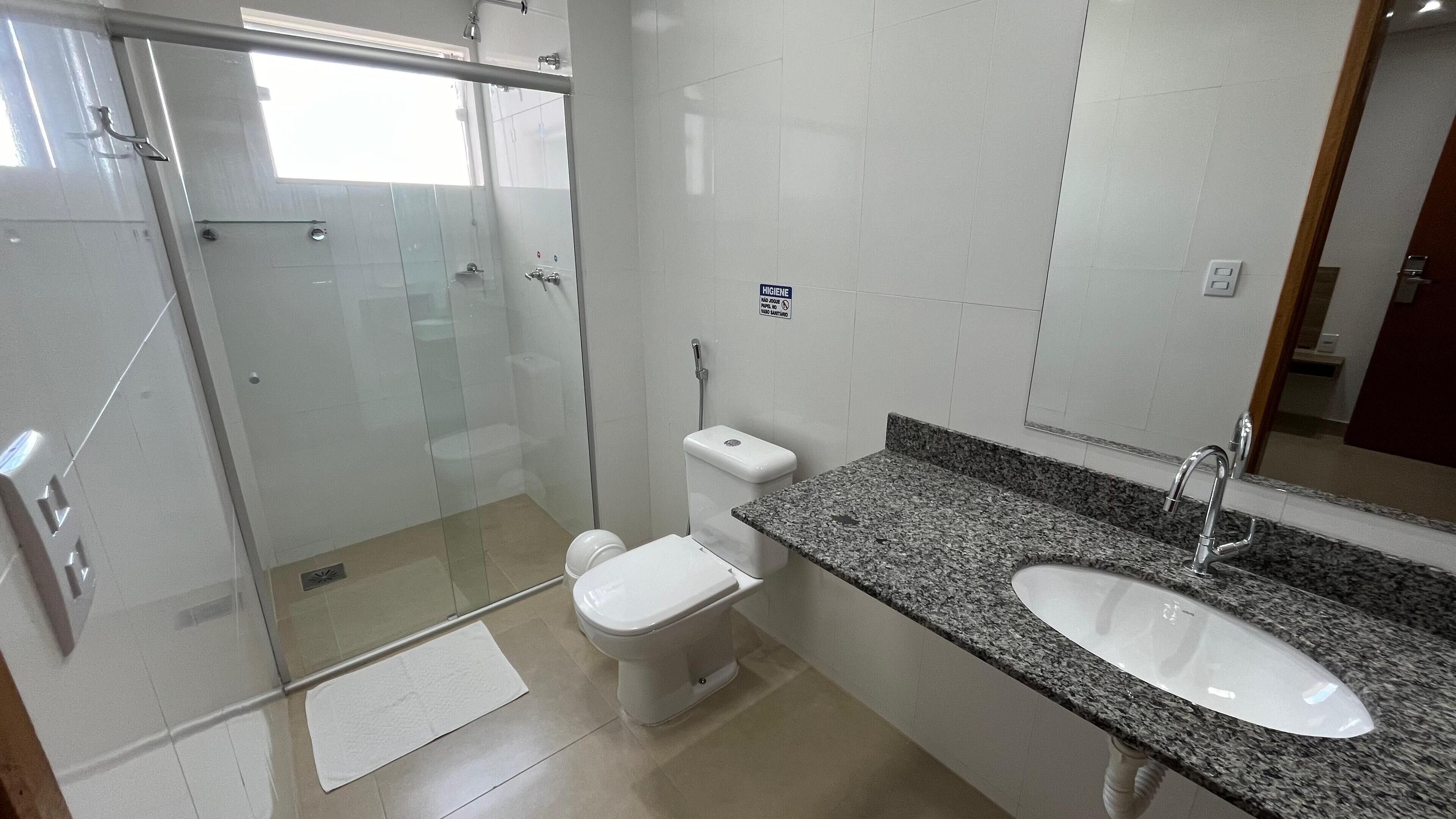 Een moderne badkamer met een douchecabine van glas, een toilet en een wastafel met een granieten blad.