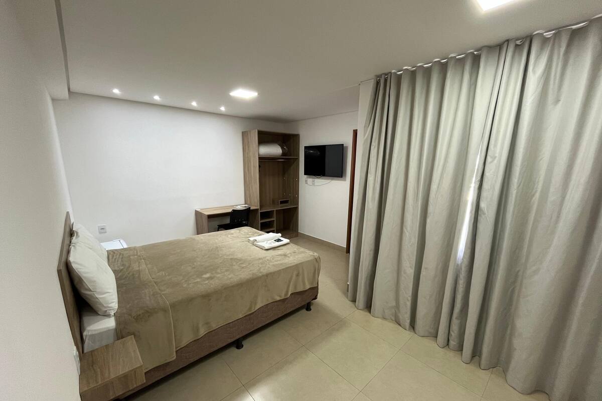 Una habitación de hotel con cama, escritorio, televisión y armario.