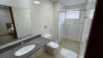 Uma casa de banho moderna com lavatório de bancada em granito, sanita e cabine de duche envidraçada.